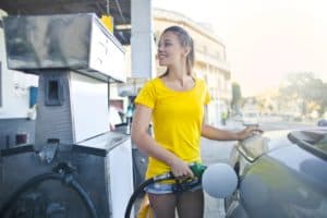 A girl pumps diesel fuel from a green pump handle at a gas station