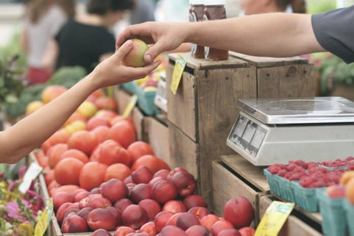 A person at a farmers' market buys apples