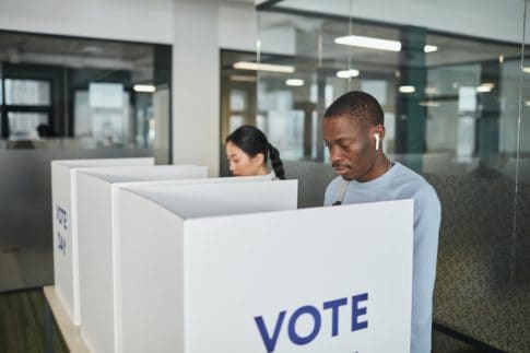Two people vote in a voting booth, this is how to vote when RVing