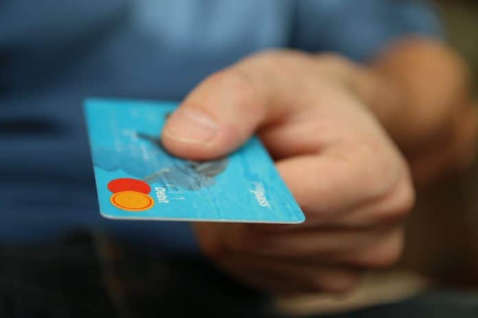A person holds out a credit card to pay for the true cost of RV living