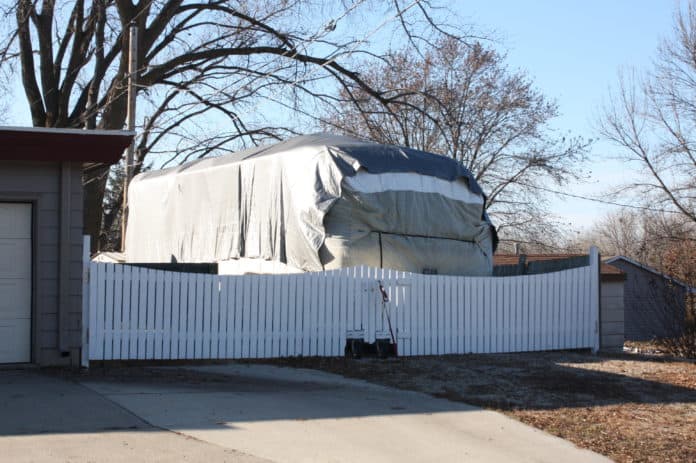A tarp covers this RV that is stored outside