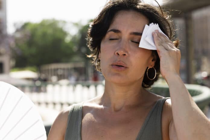 A woman wiping sweat off in hot summer temperatures