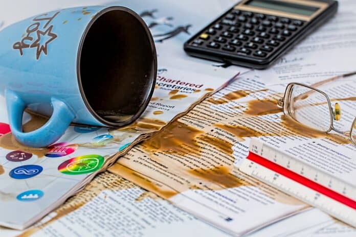 A spilled coffee mug leaves a stain on desk and papers
