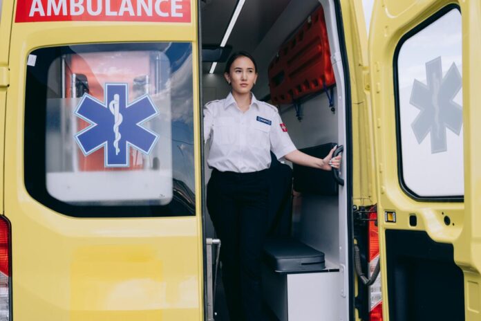 A woman stands in the back of an ambulance helping someone who just had a heart attack while RVing