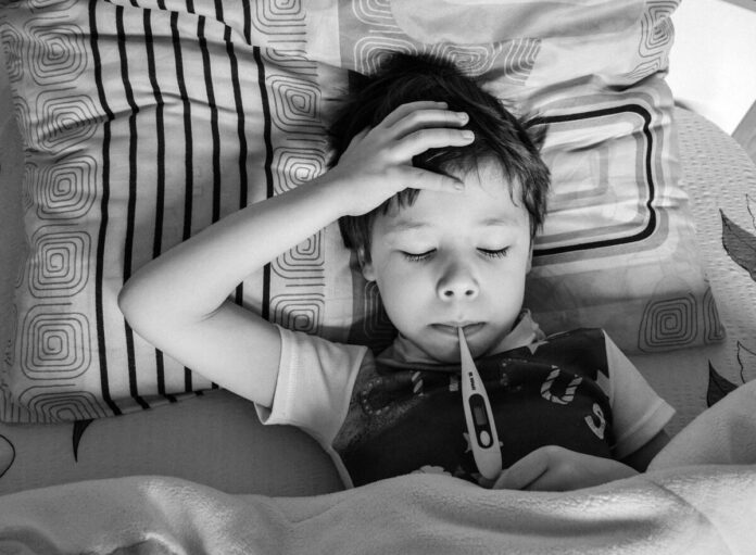 A little boy with a fever takes his temperature even though he tried to avoid getting sick while rving