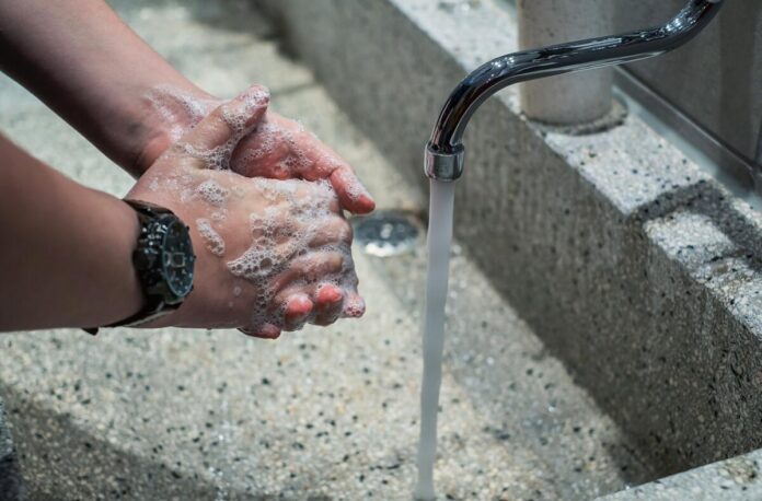 A man washing his hands in a public bathroom sink