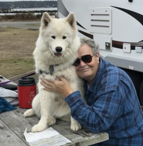 A samoyed dog and human on a picnic table at a campgrond