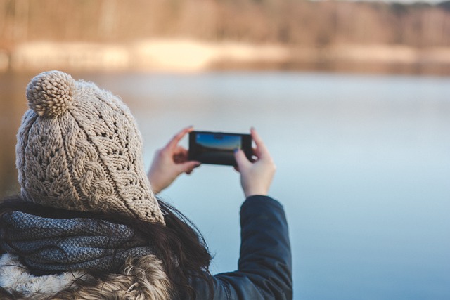 outdoor winter photo of girl taking a photo with her cell phone camera