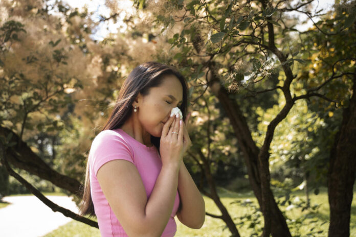 side view of woman sneezing on a story about managing allergies