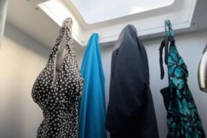 RV swimsuit season hack shows swimsuits hanging in an RV shower