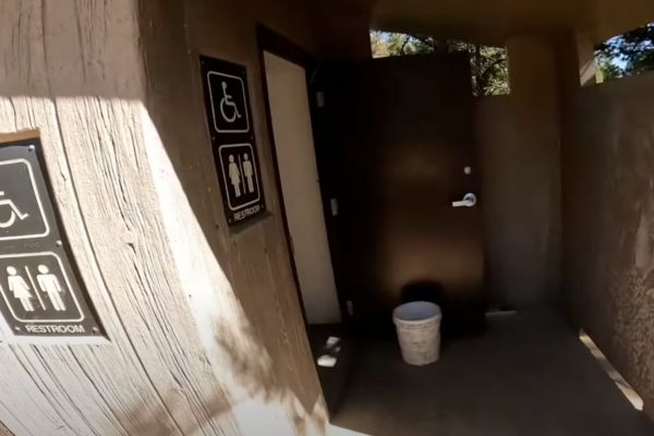 Title photo for a post on camp host duties showing a campground vault toilet