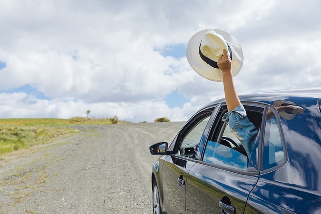 Car with driver breezily waving hat out window Pixabay image