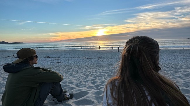 Family sitting on the beach at sunset